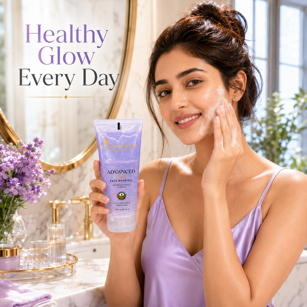 A woman in a lavender satin robe applies face wash cream to her cheek while holding a tube of Advanced Face Wash by The Skincare Institute. She is standing in a bright, modern bathroom with gold fixtures, a mirror, and a vase of purple flowers.