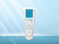 A white squeeze tube of Acelak 4in1 Pimple Care Face Wash with a blue label block, centered against a light blue gradient background with soft light rays.